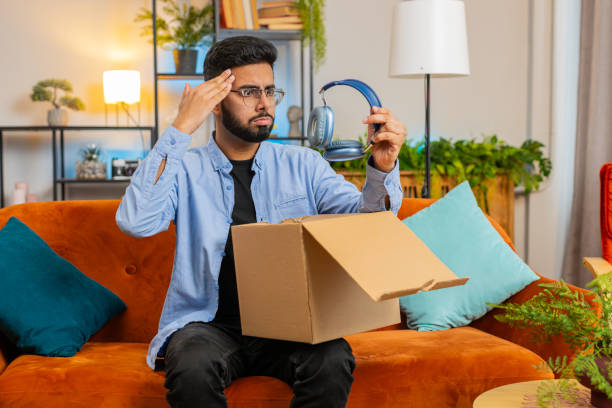 istock Dissatisfied Indian man customer open cardboard box receive damaged broken wireless headphones 2178147284