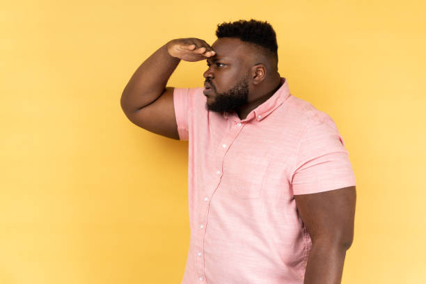 istock Side view of curious man with beard keeping palm over head and looking attentively far away. 2178147932