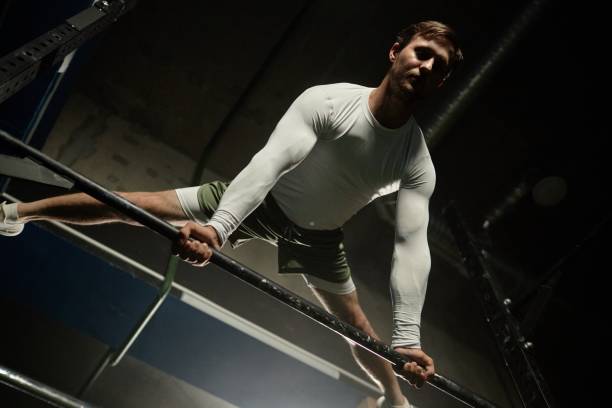 istock Strong Man Holding Straddle Planche on High Bar Exercising Calisthenics in Gym 2178153726