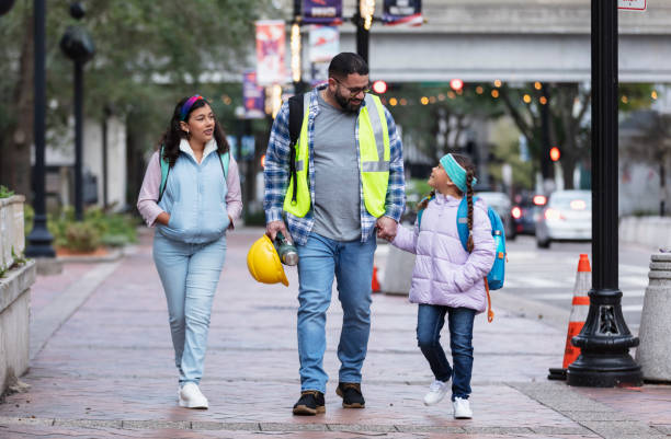 Hispanic father taking daughters to school in city