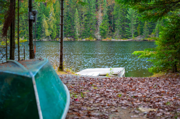 Low close-up of small wooden pier and canoe on a lake during autumn with trees in background
