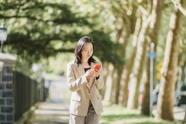 istock Peaceful walk: woman engages with her smartphone under a tree canopy 2178157847