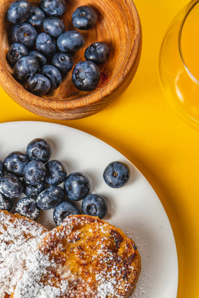 French toast on a white plate with blueberries and orange juice for breakfast