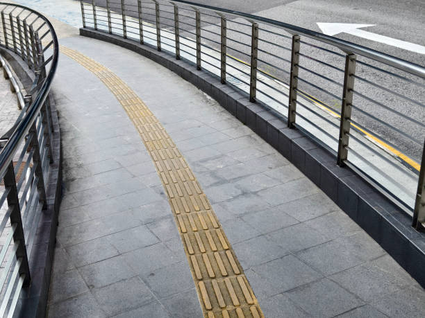 istock Curved path with guardrail and yellow line for blind people along the road 2178169125