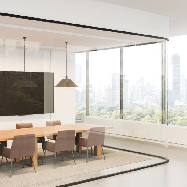 istock Stylish office interior with meeting table and armchairs, tv screen and window 2178169628