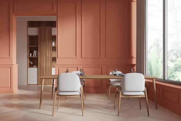 istock A modern dining room with peach-colored walls, a wooden table, and white chairs. Large windows overlooking greenery. Bright and airy interior. 3D Rendering 2178170381