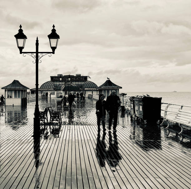 Tourists reflected on the floor of Cromer Pier in the rain on an Autumn day
