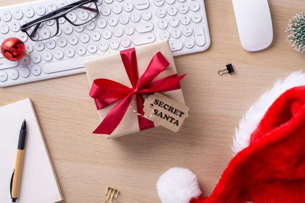 istock Christmas-themed office desk featuring a wrapped present with a red bow, keyboard, Santa hat, and decorative items, symbolizing holiday spirit and workplace celebration 2178175896