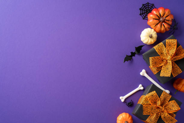 istock Halloween gift boxes with orange bows, surrounded by pumpkins, bones, and bats on a purple background 2178175908