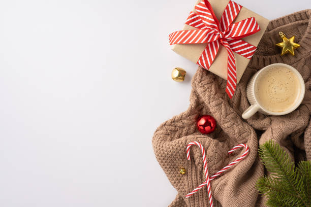 istock A cozy winter setting featuring a wrapped gift, festive ornaments, a warm drink, and candy canes on a knitted blanket 2178175912