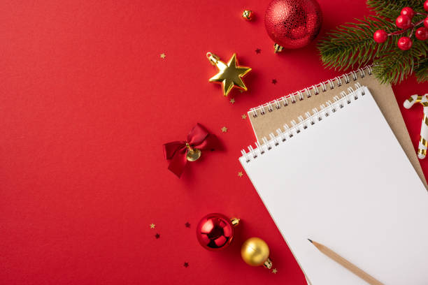 istock Festive holiday scene with Christmas ornaments and empty notebook on a red background, perfect for planning or resolutions 2178175933