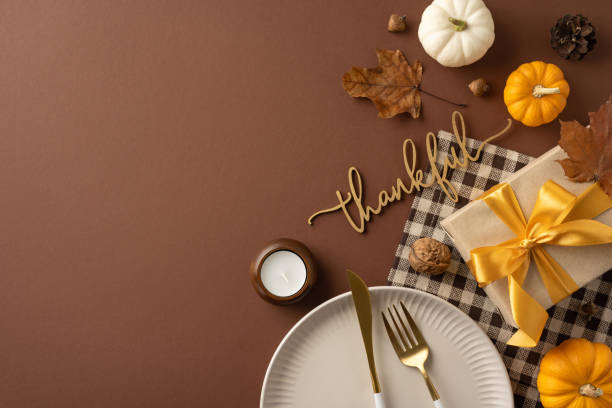 istock Elegant Thanksgiving table setting featuring pumpkins, a gift box with a bow, decorative leaves, and a thankful sign. Ideal for celebrating gratitude and holiday gatherings 2178175935
