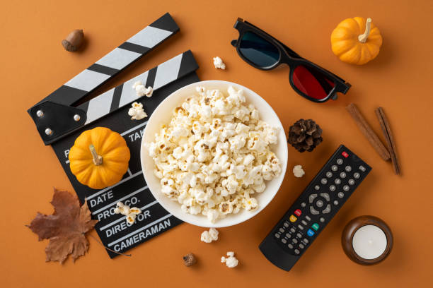 istock A cozy autumn movie night setup featuring popcorn, pumpkins, a clapperboard, 3D glasses, and a remote control on a warm background 2178175987