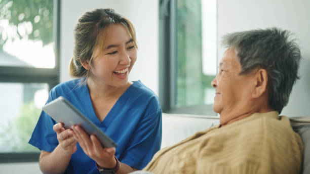 istock Home caregiver using technology health with her elderly patient. 2178177066