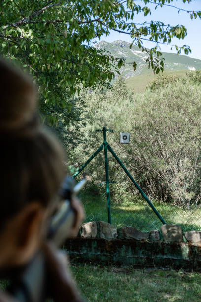 istock Rear view Defocus woman is shooting a gun at a target 2178187203