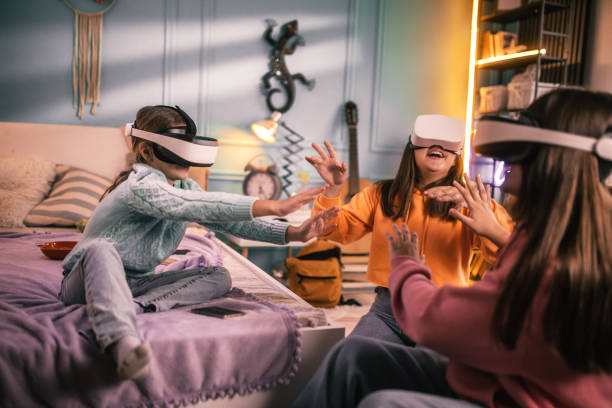 istock Cheerful friends looking through virtual reality simulators while sitting on couch at home 2178187979