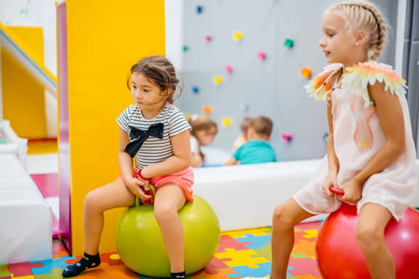 istock Two Girls Bouncing On Hopper Balls In Kid's Playroom 2178192100