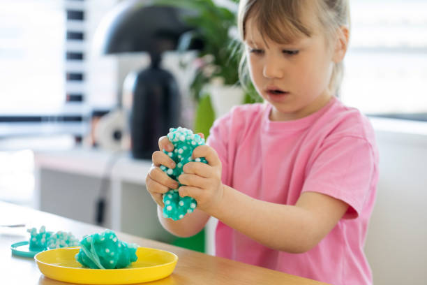 istock A cute girl playing with bright, blue slime, enjoying a fun and creative indoor activity. 2178192776