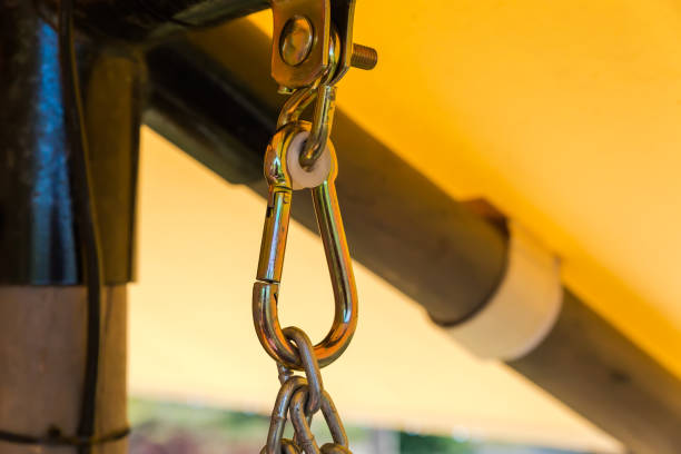 Metal suspension unit consisting of bracket with bolt, hook, suspension carabiner and chain for swing hanging, or swing bench on a blurred background of garden structure