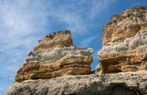 Stunning view of towering natural rock formations against a bright blue sky, showcasing the beauty of geological structures and serene outdoor landscapes. in lagos in Portugal