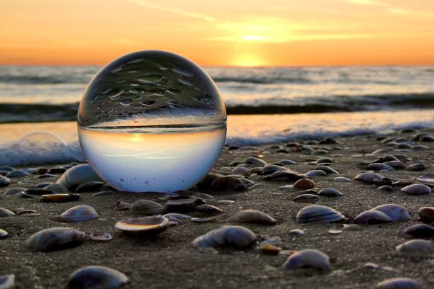 istock Crystal ball on the beach on shells during sunrise 2178202167