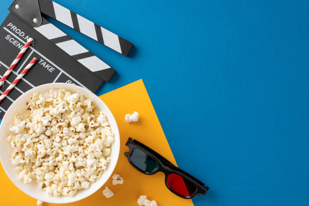 istock Top view of a popcorn bowl, clapperboard, and 3D glasses on colorful background, representing a fun movie night atmosphere 2178202461
