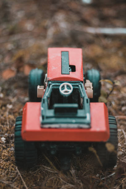 Closeup of a red toy tractor placed on the ground during autumn