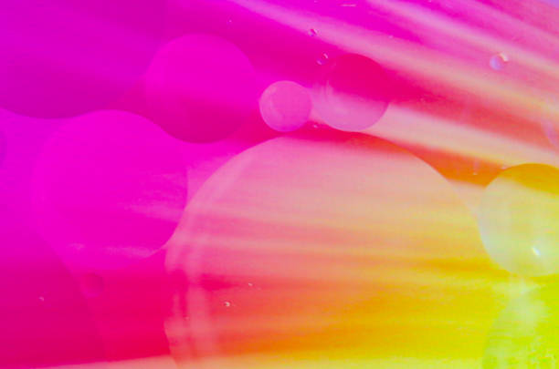 Oil bubbles merging and shifting on a water surface, with a smooth gradient in the backdrop, ideal for a wallpaper.