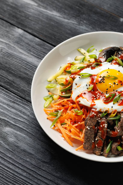 istock Traditional Korean dish Bibimbap with rice, vegetables beef and egg in a white plate 2178216915