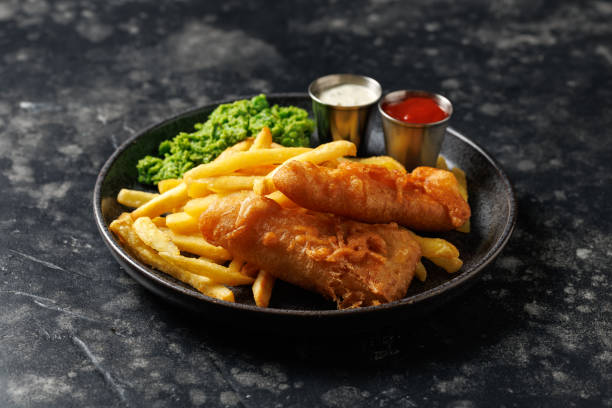 istock British Fish and chips with mashed peas, tartar and ketchup sauce. 2178216955