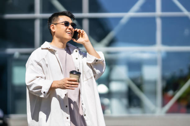 istock A man in a shirt with rolled-up sleeves and glasses talks on a mobile phone while standing near a mirror building 2178222498