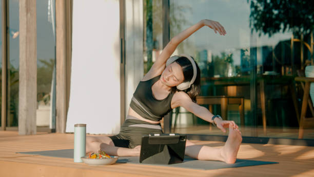 istock Young Asian woman training her flexibility during an online yoga class at home. 2178229933