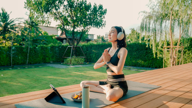 istock Young Asian woman folding her hands while doing yoga peacefully at home. 2178229936