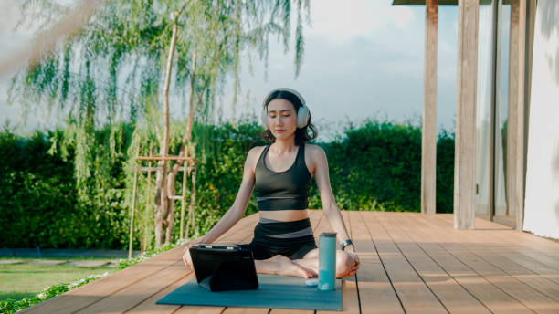 istock Young Asian woman stretching her muscles while doing a yoga exercise peacefully at home. 2178229944