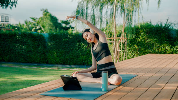 istock Young Asian woman stretching her muscles while doing a yoga exercise peacefully at home. 2178229946