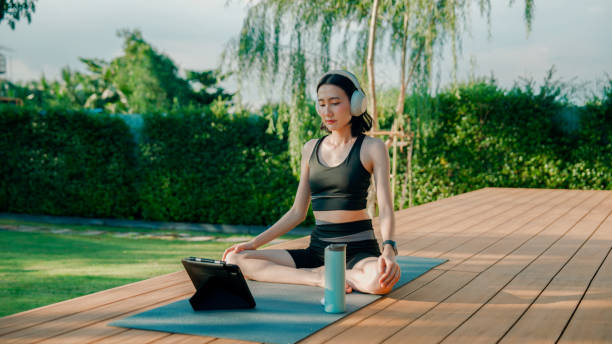 istock Young Asian woman training her flexibility during an online yoga class at home. 2178229954