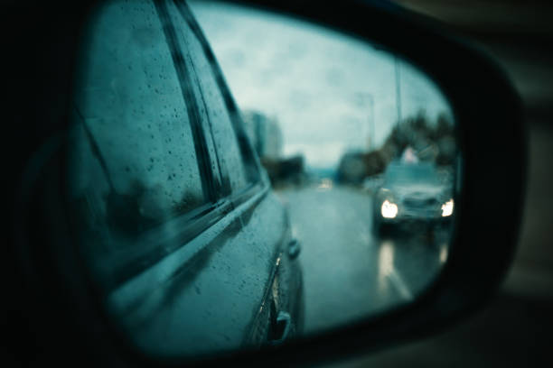 Side view mirror of a car on a rainy autumn day, selective focus