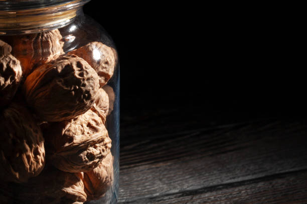 walnuts glass jar on black wood background