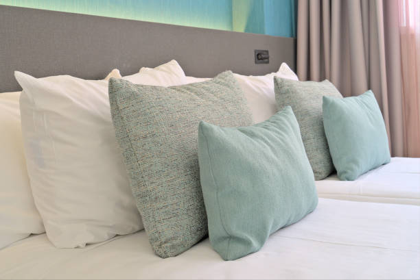 Decorative turquoise pillows on a neatly made bed with modern gray and teal backdrop in a stylish hotel room