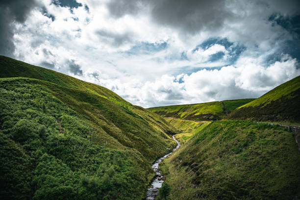 Little stream between two hills and a curvy road in Yorkshire, UK