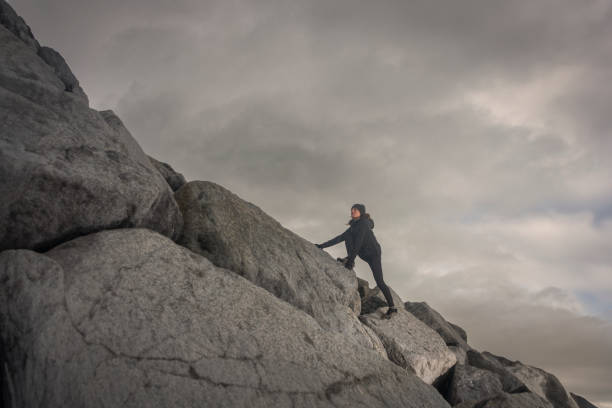 Woman climbing up rocks to the summit