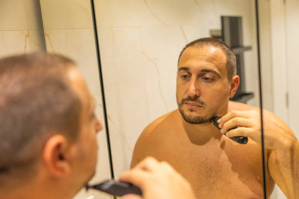 istock Oversized man standing in the bathroom and shaving his beard using an electric shaver. 2178247800