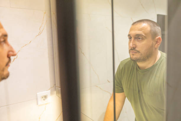 istock Men is looking at the mirror in the bathroom. 2178248129