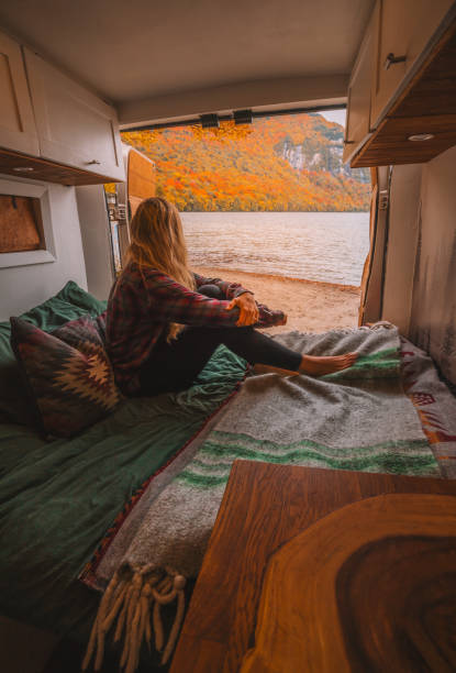 istock Girl in Bed Camper Van Interior Doors Open Remote Destination Digital Nomad Fall Foliage Autumn Season. Outdoors Lake Vermont New England Off The Grid 2178248771