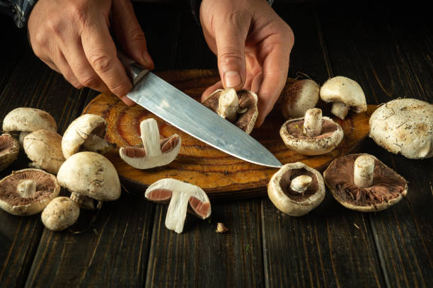 istock Chef slices champignons mushrooms on a cutting board before cooking. Concept of preparing mushrooms for a tasty dinner 2178253194