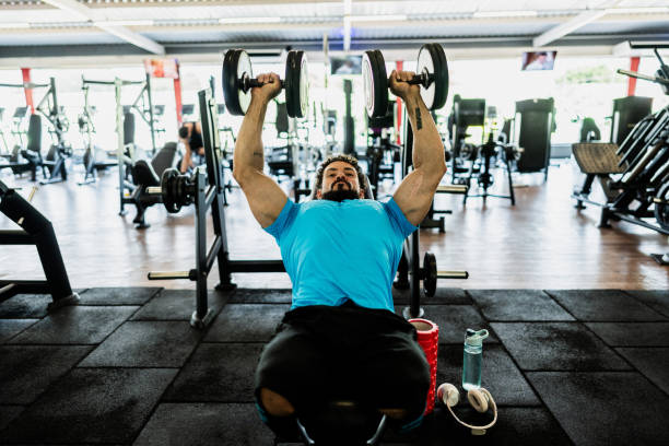 istock Mid adult man doing exercises on bench press at gym 2178253283