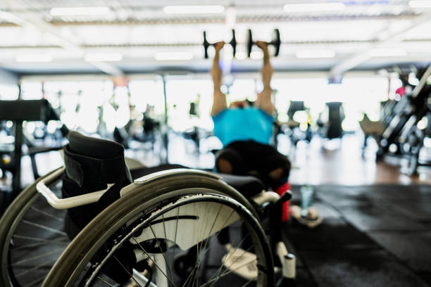 Cropped view of a person attending to individual in wheelchair on carpet. Scene depicts caregiving for someone with mobility challenges in home environment