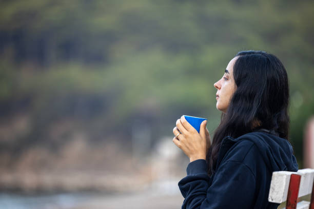 A woman drinking coffee at the beach