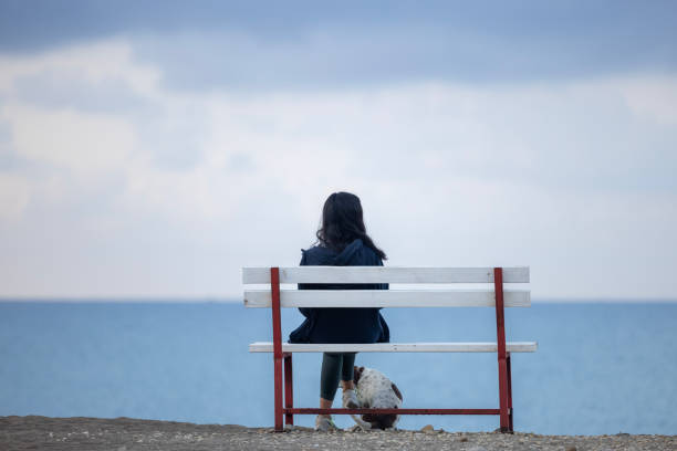 A lonely woman is sitting on a bench at the beach
