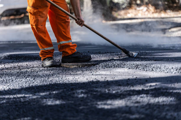 istock Worker repairing a road surface on a sunny day, wearing orange overalls and using a tool for asphalt application in a residential area 2178256354